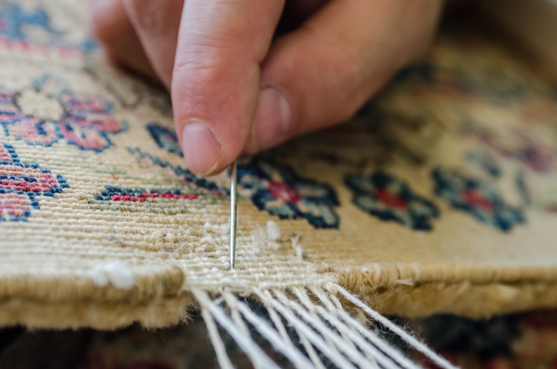 Close up of professional's hand re-knotting/re-weaving a damaged, worn rug - Rug Restoration - Springfield, IL