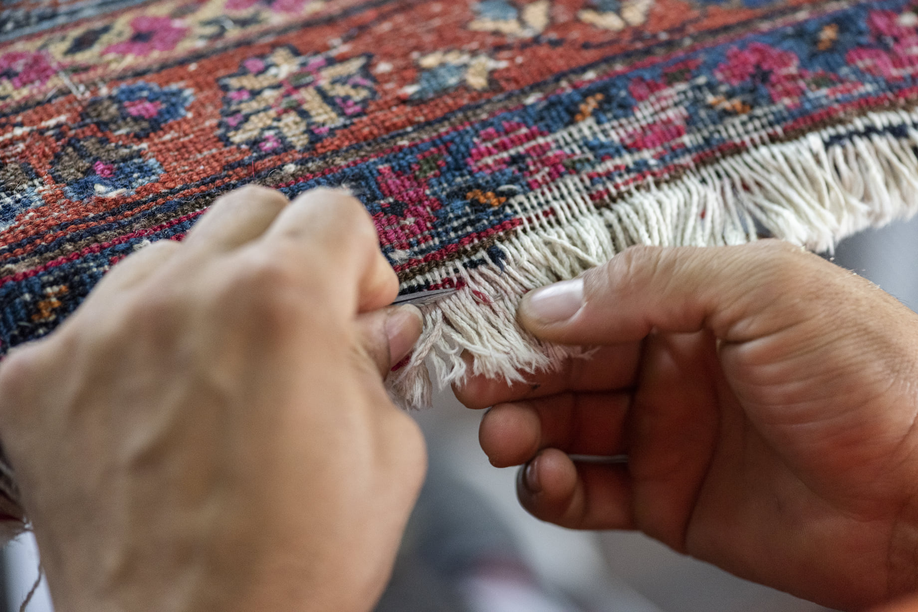 close up of professional hands repairing the fringe on an antique Persian rug - Springfield, IL