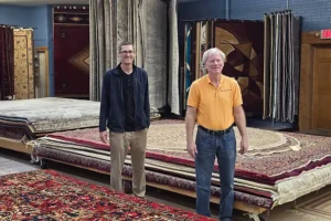 Representatives of The Rug Rack & Murphy Rug Cleaners stand in the showroom in Springfield, IL surrounded by hundreds of rugs.