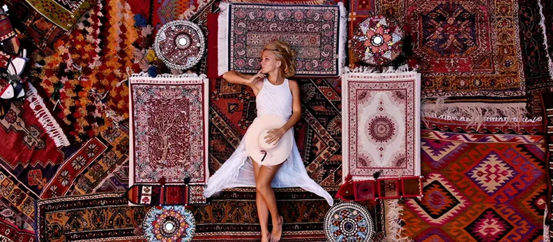 A young woman in white lying on dozens of different rugs with different patterns and colors in Springfield, IL.